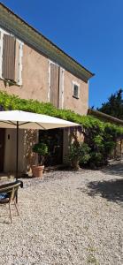 a patio with an umbrella in front of a building at Cherche Midi in Noves