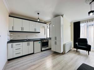 una cocina con armarios blancos y una silla negra en Modern Cozy Apt For Large Group and Families, en Estambul