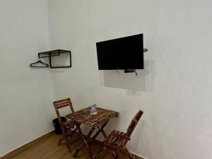 een tafel met twee stoelen en een televisie aan de muur bij Quinta del Valle Suite Jr 3 2pax in Valle de Bravo