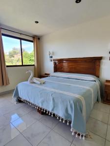 a bedroom with a large bed with a swan on it at Hotel Posada Camelinas in P&aacute;tzcuaro
