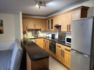 a kitchen with wooden cabinets and a white refrigerator at 2 Bedroom Modern stylish Apt in Glasgow City Centre in Glasgow