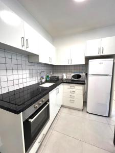 a kitchen with white cabinets and a sink and a refrigerator at Apartments4you Maria in Bat Yam
