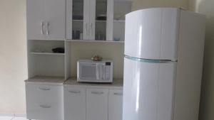 eine Küche mit einem weißen Kühlschrank und einer Mikrowelle in der Unterkunft Casa do Bruno in Olímpia