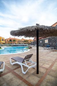 Una tumbona bajo una sombrilla junto a una piscina. en Apartamento BOREAS PARADISE Costa del Silencio, en Costa del Silencio 27 fotos más