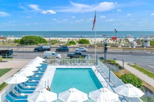 una piscina con ombrelloni e un parcheggio con la spiaggia di Mahalo Cape May a Cape May