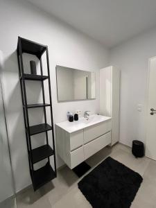 La salle de bains est pourvue d'un lavabo blanc et d'un miroir. dans l'établissement Appartement NEUF et LUXUEUX à Liège, à Seraing