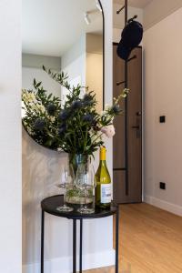 a table with a vase of flowers and wine glasses at Monciak Elegance - Plaża in Sopot