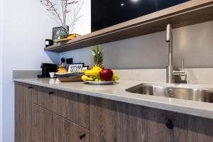 a bowl of fruit on a kitchen counter with a sink at Monciak Elegance - Plaża in Sopot