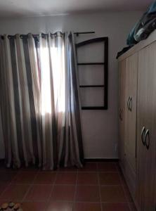 a room with a window with a curtain and a cabinet at Espaço familiar in Maricá