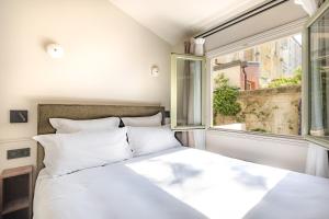 um quarto com uma cama branca e uma janela em Maison du Moulin Vert em Paris