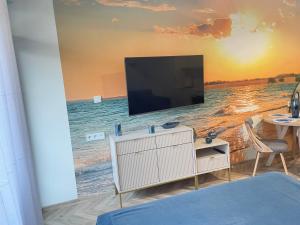 a living room with a television on a beach at Apartament Morski Spokój Solny Resort in Kołobrzeg