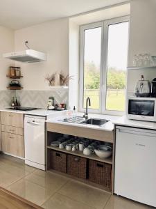 a white kitchen with a sink and a microwave at Maison Moz in Fontaines-en-Sologne