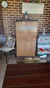 a refrigerator and a chair and a clock on a brick wall at Espaço familiar in Maricá