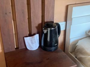 a coffee pot sitting on a table next to a bed at Bhuvi Wayanad Natural Tea Plantation Resort in Wayanad