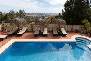 a swimming pool with chairs and a view of the city at Bed & Breakfast Villa Botánica in Málaga