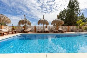 a swimming pool with chairs and umbrellas at Bed & Breakfast Villa Botánica in Málaga