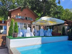 - un groupe de chaises et un parasol à côté de la piscine dans l'établissement Casa de vacanță MARA emd, à Eşelniţa