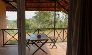 um quarto com uma mesa e uma varanda com vista em Bhuvi Wayanad Natural Tea Plantation Resort em Wayanad