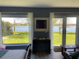 1 dormitorio con 1 cama y 2 ventanas grandes en The Cosy Studio by the shore, en Galway