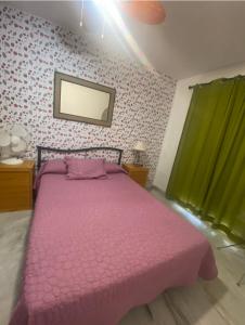 ein Schlafzimmer mit einem rosa Bett und einem grünen Vorhang in der Unterkunft Apartamento El Mirador in Aguadulce