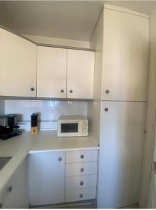 eine Küche mit weißen Schränken und einer weißen Mikrowelle in der Unterkunft Apartamento El Mirador in Aguadulce