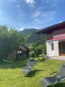 due sedie sedute nell'erba accanto a una casa di Chalet Panoramablick Zell am See a Zell am See
