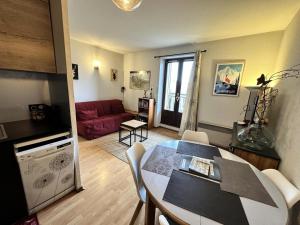 ein Wohnzimmer mit einem Tisch und einem roten Sofa in der Unterkunft Résidence Le Grand Adret - 2 Pièces pour 4 Personnes 024 in Villard-de-Lans