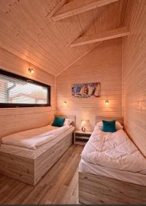 two beds in a room with wooden walls at DOMKI LETNISKOWE MORZA SZUM in Bobolin
