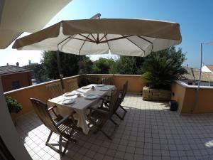- une table et des chaises avec un parasol sur la terrasse dans l'établissement Attico con terrazzo, à San Costanzo