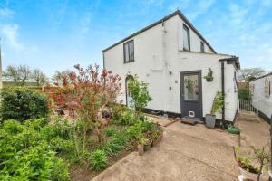 Lily Cottage In Idyllic Reedham في Reedham: اطلالة خارجية على بيت ابيض مع حديقة