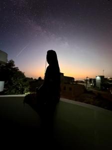 a woman sitting on a ledge looking at the night sky at keur manga in Somone
