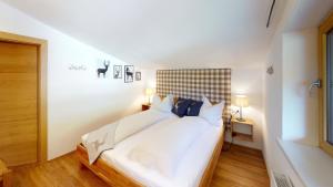 ein Schlafzimmer mit einem weißen Bett mit einem karierten Kopfteil in der Unterkunft Alpine Style Kaprun in Kaprun