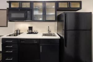 uma cozinha com um frigorífico preto e um lavatório em Candlewood Suites Philadelphia - Airport Area, an IHG Hotel em Chester