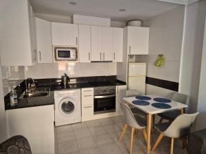 una cocina con armarios blancos y una mesa con sillas. en Gladmar Apartment, en La Mata