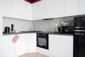 a kitchen with white cabinets and a black refrigerator at Apartament Bajka in Grudziądz