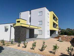a white and yellow building with plants in front of it at Apartment Mila in Ugljan