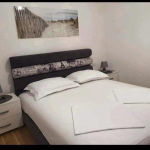 een wit bed met 2 kussens in een slaapkamer bij Holiday Apartment in Budva