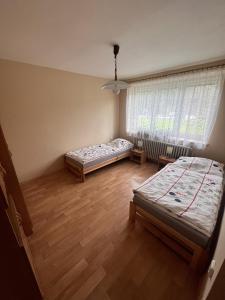 two beds in a room with wooden floors and a window at Rekreační dům Pod Břízou in Rudník