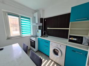 a kitchen with blue cabinets and a washing machine at Romanescu One Apartament in Craiova