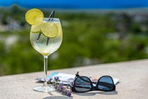 ein Glas Wein mit Limette auf einem Tisch mit Sonnenbrille in der Unterkunft Akadémia Hotel in Balatonfüred