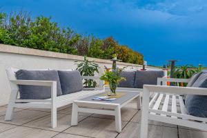 2 weiße Stühle und ein Tisch auf der Terrasse in der Unterkunft Akadémia Hotel in Balatonfüred