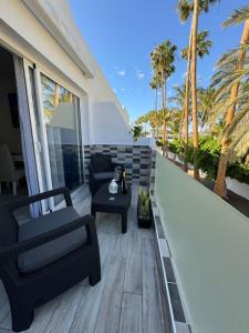 a balcony with a chair and a table and palm trees at Brisa del mar in Tarajalejo