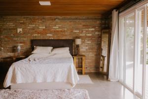 1 dormitorio con cama y pared de ladrillo en Chalé Deckmont en Caraa