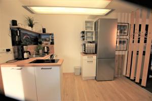 cocina con armarios blancos y nevera en Westerwald Apartment DRIE600, en Driedorf