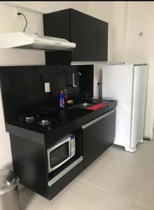  Il comprend une cuisine noire équipée d'un four micro-ondes et d'un réfrigérateur. dans l'établissement Apartamento studio, à Maceió