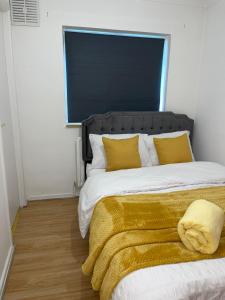 1 dormitorio con 1 cama grande con almohadas amarillas en Stevenage Studios - Superior Suite, en Stevenage