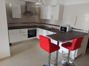 - une cuisine avec des placards blancs et des chaises rouges dans l'établissement Apartamento Bajamar Tenerife, à Bajamar