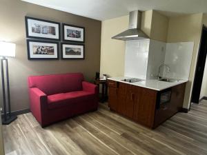 a living room with a red couch and a kitchen at Wingate by Wyndham College Station TX in College Station