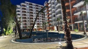 a large apartment building with a swimming pool and palm trees at Princ Apartment studio in Shëngjin