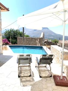 ein Paar Stühle und ein Sonnenschirm neben einem Pool in der Unterkunft Pool House ( Πέτρινο σπίτι με πισίνα ) in Itylo